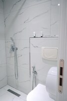 A modern bathroom with a shower, toilet, and a hand dryer.