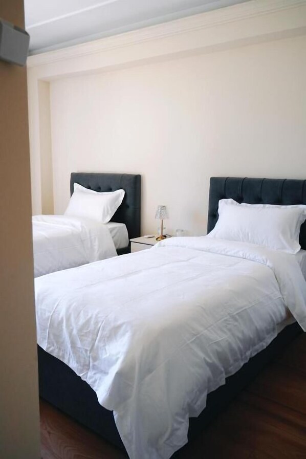 Hotellihuone, jossa on kaksi sänkyä, ja jokaisessa on tumma pääty ja valkoiset vuodevaatteet.