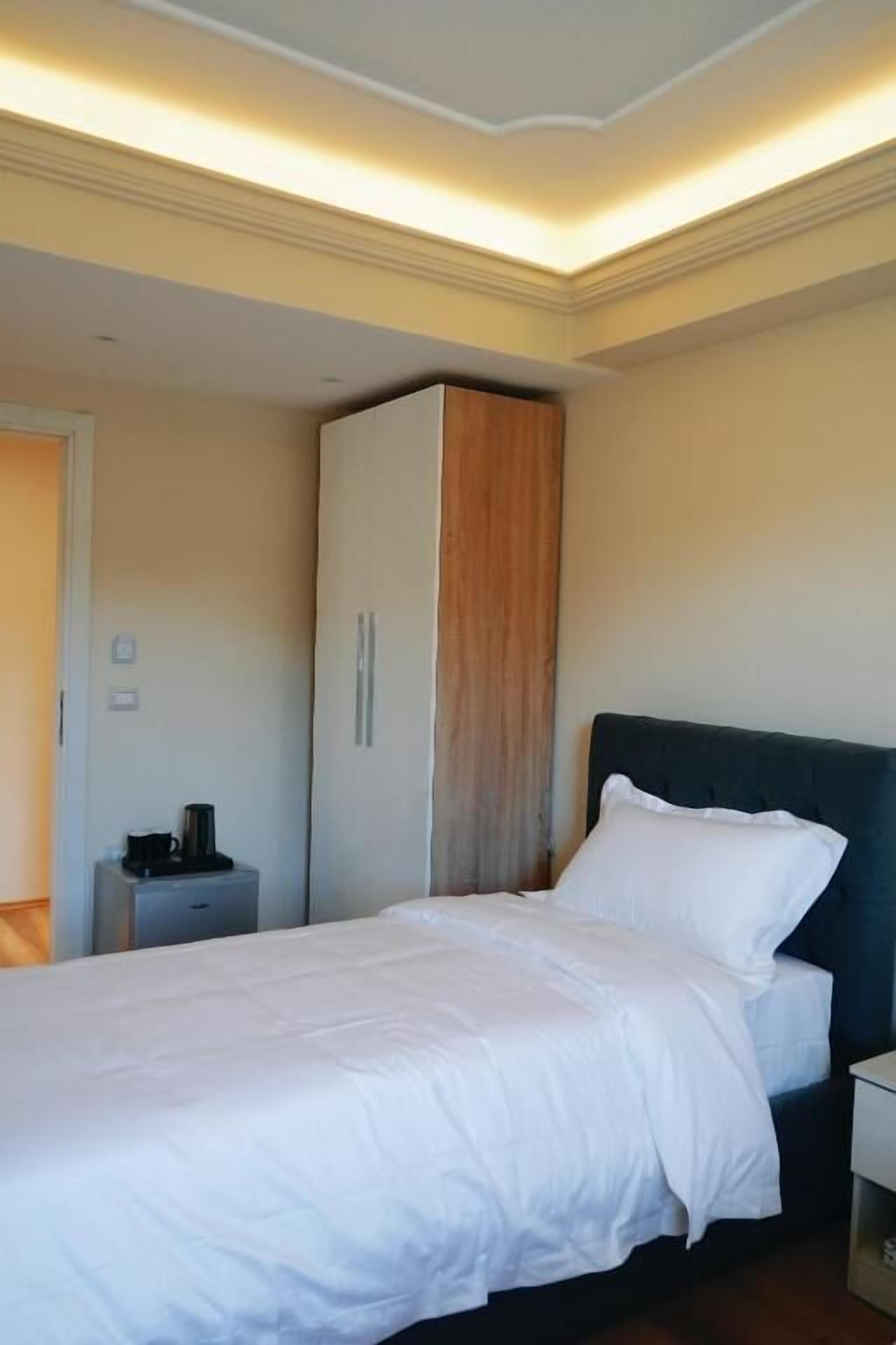 A bedroom with a bed, a wardrobe, and a bedside table.