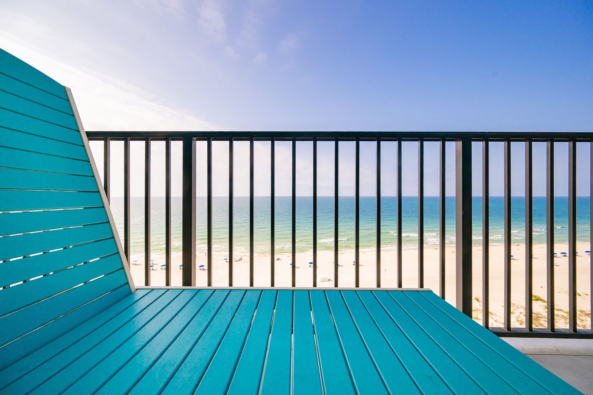 A balcony with a view of the beach and ocean.