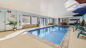 An indoor swimming pool with clear glass walls, potted plants, and sunlit windows. - 5023 Gateway 2 Bedroom Condo (Keystone)