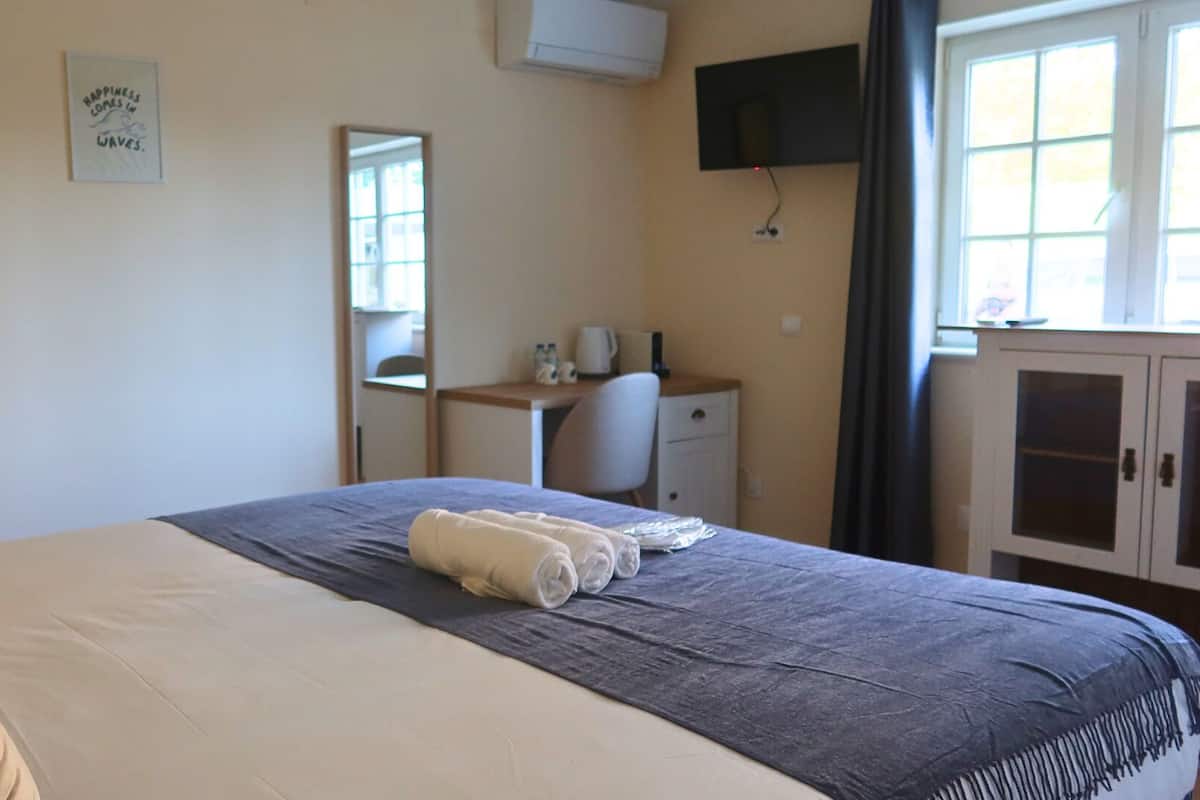 Een hotelkamer met een bed, een bureau, een stoel, een televisie en een kast.