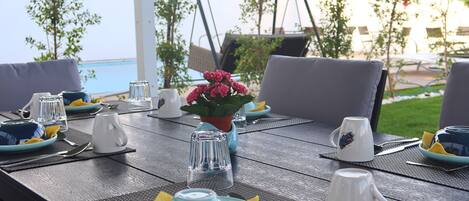 An outdoor dining area with a table set for two, featuring a view of the sea.