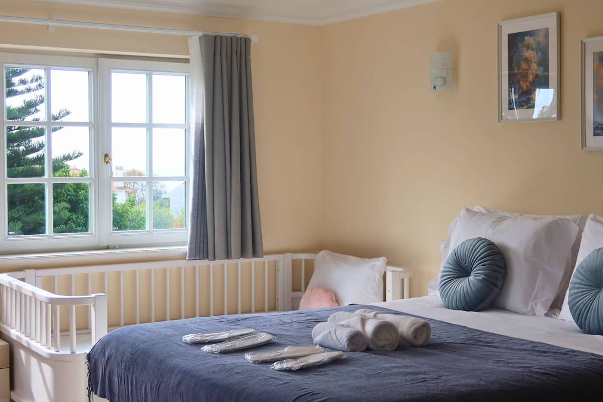 Een slaapkamer met een groot bed, een raam met gordijnen en drie ingelijste kunstwerken aan de muur.
