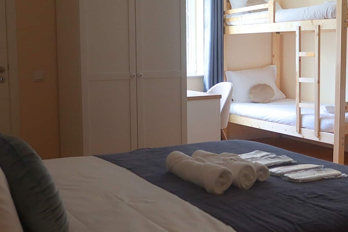 Een kamer met een bed, een bureau en een stapelbed.