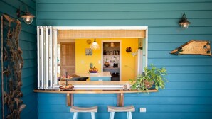 A kitchen with a yellow wall, a window, and a plant on the counter. - Casa Mariposa (Riordanvale)