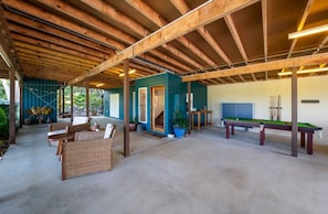 An indoor recreational area with a pool table, seating, and a covered patio. - Casa Mariposa (Riordanvale)