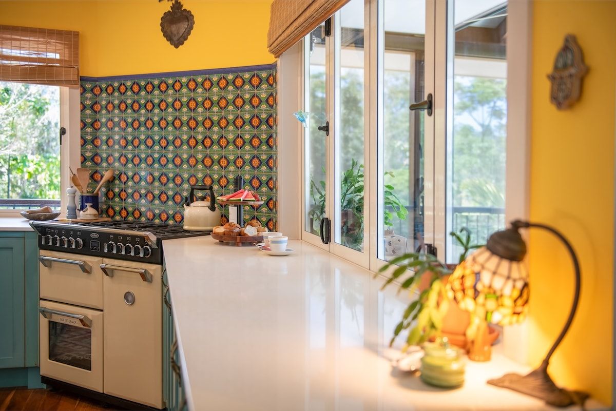 A kitchen with a stove, oven, and a window with a view of greenery.