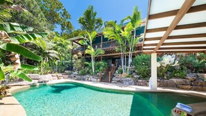 A clear pool surrounded by tropical plants and a multi-level wooden structure. - Casa Mariposa (Riordanvale)
