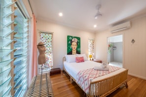 A bedroom with a bed, a bedside table, a mirror, and a window with curtains. - Casa Mariposa—A Secluded Tropical Sanctuary (Riordanvale)