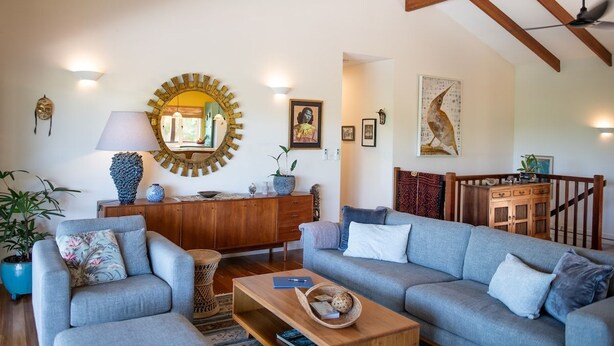 A living room with a sofa set, a coffee table, a lamp, a mirror, and a wooden cabinet. - Casa Mariposa (Riordanvale)