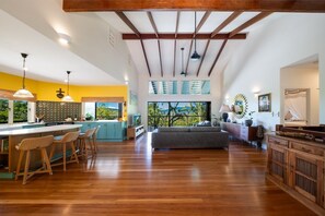A spacious living area with a kitchen island, bar stools, and a sofa. - Casa Mariposa—A Secluded Tropical Sanctuary (Riordanvale)
