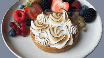 A dessert with meringue on a plate surrounded by various berries.