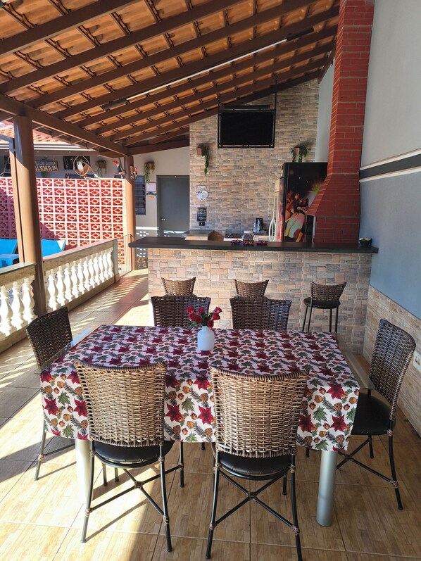 Un patio al aire libre con chimenea de ladrillo, sillas de mimbre y una mesa con mantel floral.