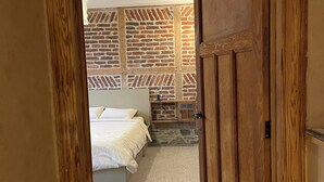 A bedroom with a bed, a wooden door, and a brick-patterned wall. - Le grand Second, charming gîte for 5 people near Spa town center. (Spa)