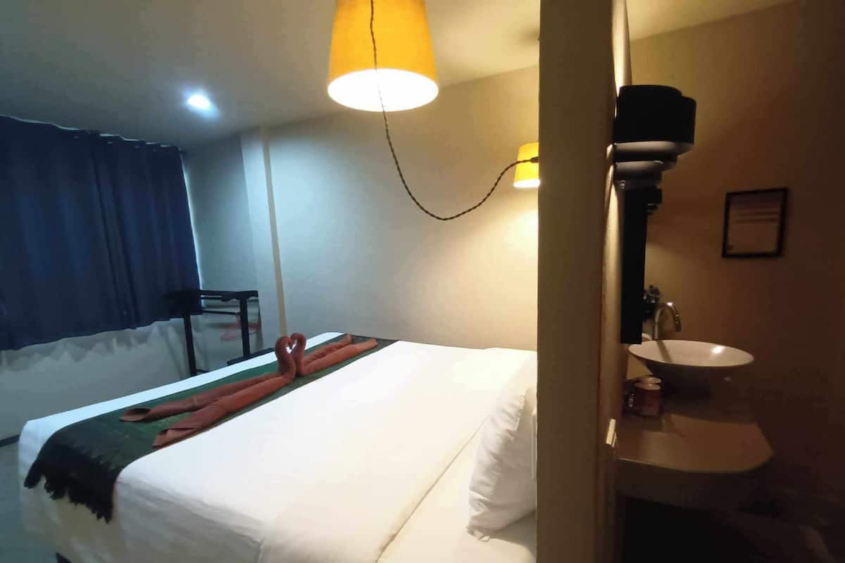Una habitación de hotel con una cama, una mesita de noche, una lámpara y un lavamanos.