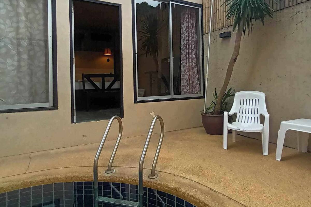 Una piscina con escalones y barandillas, una valla de madera y una planta en maceta.