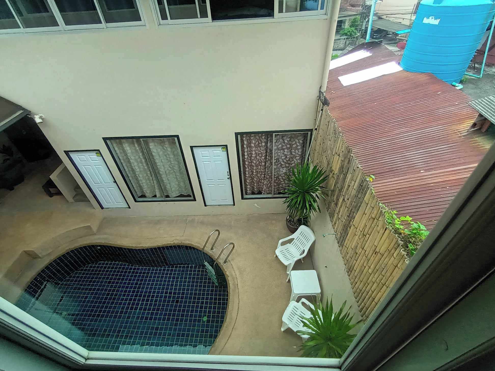 Un espace piscine aménagé sur le toit, doté d’un sol carrelé, entouré d’un petit muret et agrémenté de plantes en pot.