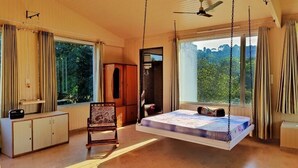 Une chambre à coucher avec un lit suspendu, une armoire en bois et de grandes fenêtres avec des rideaux.