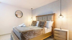 A bedroom with a bed, bedside tables, a round mirror, and pendant lights. - Luxe Apartment: By Medellín, Park, Dining, Nightlife, Fast WiFi & Self Check-in (Sabaneta)