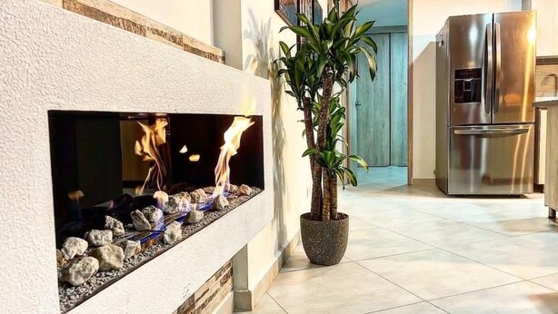 A modern kitchen with a built-in fireplace, a potted plant, and stainless steel appliances. - Luxe Apartment: By Medellín, Park, Dining, Nightlife, Fast WiFi & Self Check-in (Sabaneta)