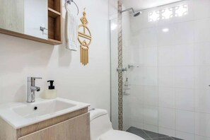 A bathroom with a white sink, a toilet, and a glass-enclosed shower.