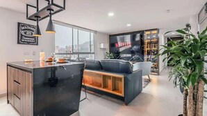 A modern living room with a black sofa, a wooden coffee table, and a TV displaying 'NETFLIX'.
