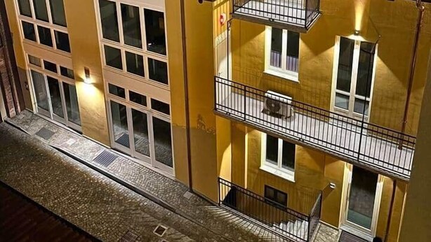 Un immeuble à plusieurs étages, doté d’une façade jaune, de grandes fenêtres et de balcons.