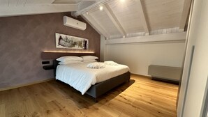 Une chambre à coucher avec un lit, un plancher en bois, un ventilateur de plafond et un climatiseur fixé au mur.