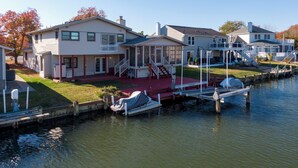 Ein Anwesen am Wasser mit Anlegesteg, überdachter Bootsrampe und einem Haus mit Veranda und Treppe zum Deck.
