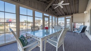 Eine überdachte Terrasse mit einem Glastisch, weißen Stühlen und einem Deckenventilator.