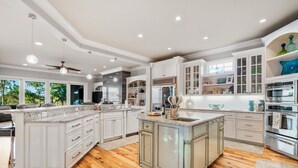 Una cocina amplia con armarios blancos, encimeras de granito y una isla grande.