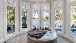 Dormitorio en esquina con un ventanal grande con vistas a un lago y una chimenea de piedra.