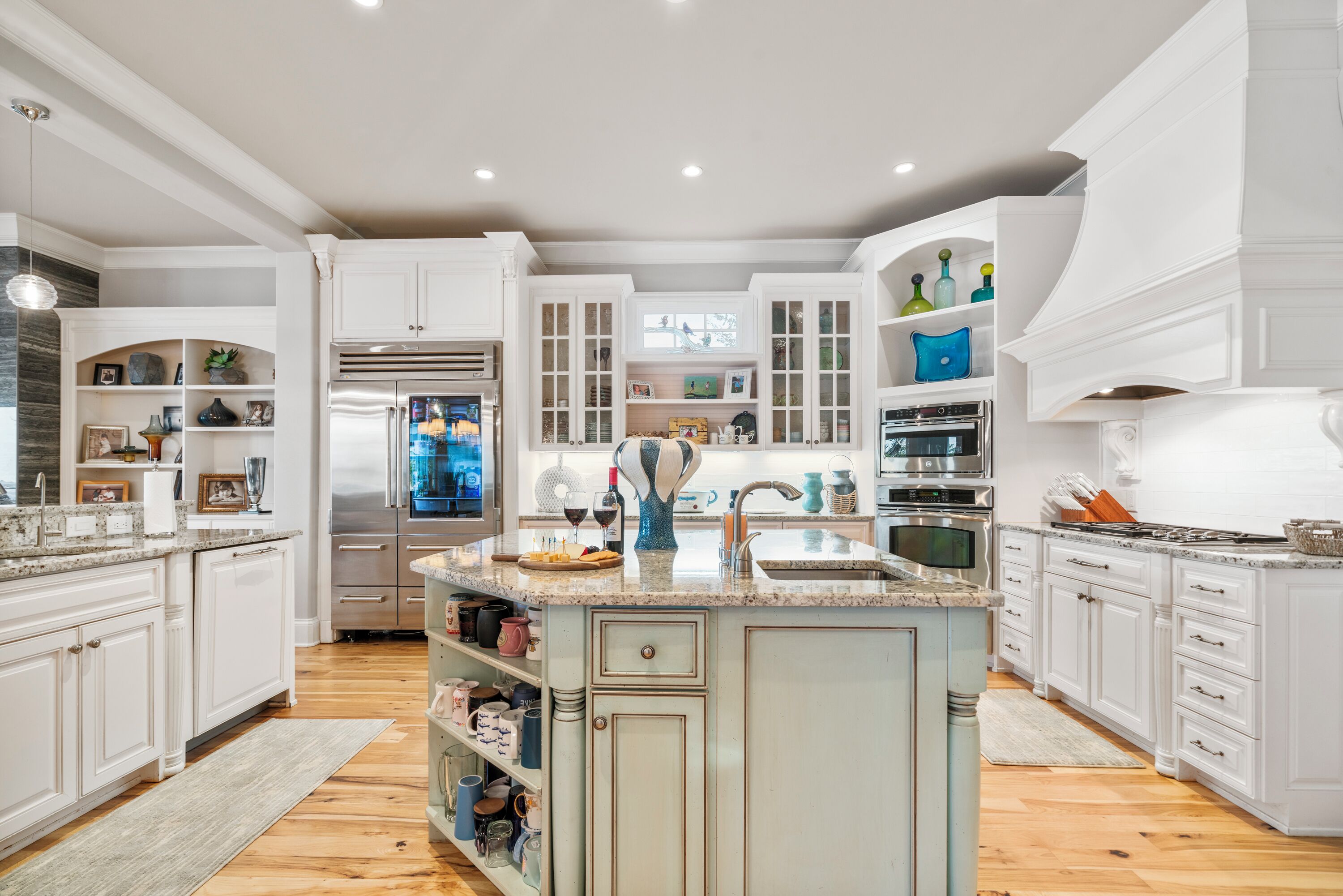 A spacious kitchen with white cabinetry, a central island, and a stainless steel refrigerator.