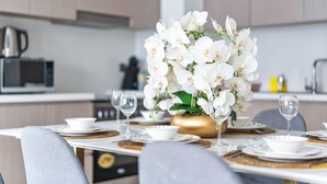 A dining table set with white plates, bowls, and gold accents, with a vase of white flowers in the center.