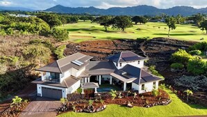 A modern two-story house with a large garage, surrounded by lush greenery and a golf course in the background.