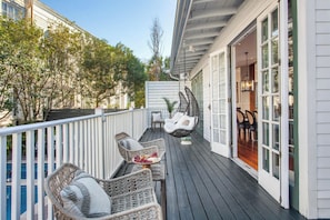 A wooden deck with wicker furniture and a glass door leading to an interior space. - 5BR NOLA B&B| Heated Pool-Hot Tub & Game Room (New Orleans)