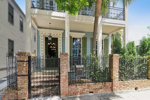 A two-story building with a gated entrance, a balcony, and a brick wall with a mailbox.