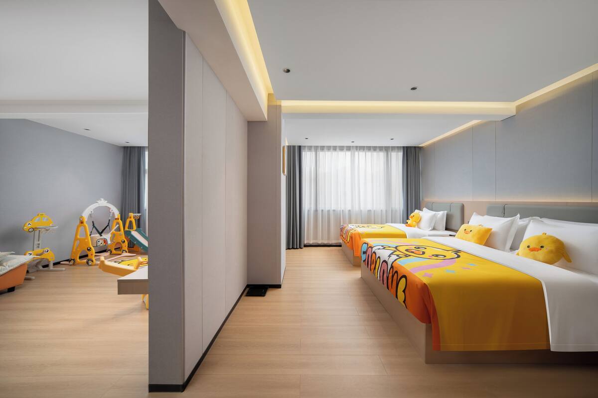 A hotel room with a bed, a desk, and a chair. There is a window with curtains.