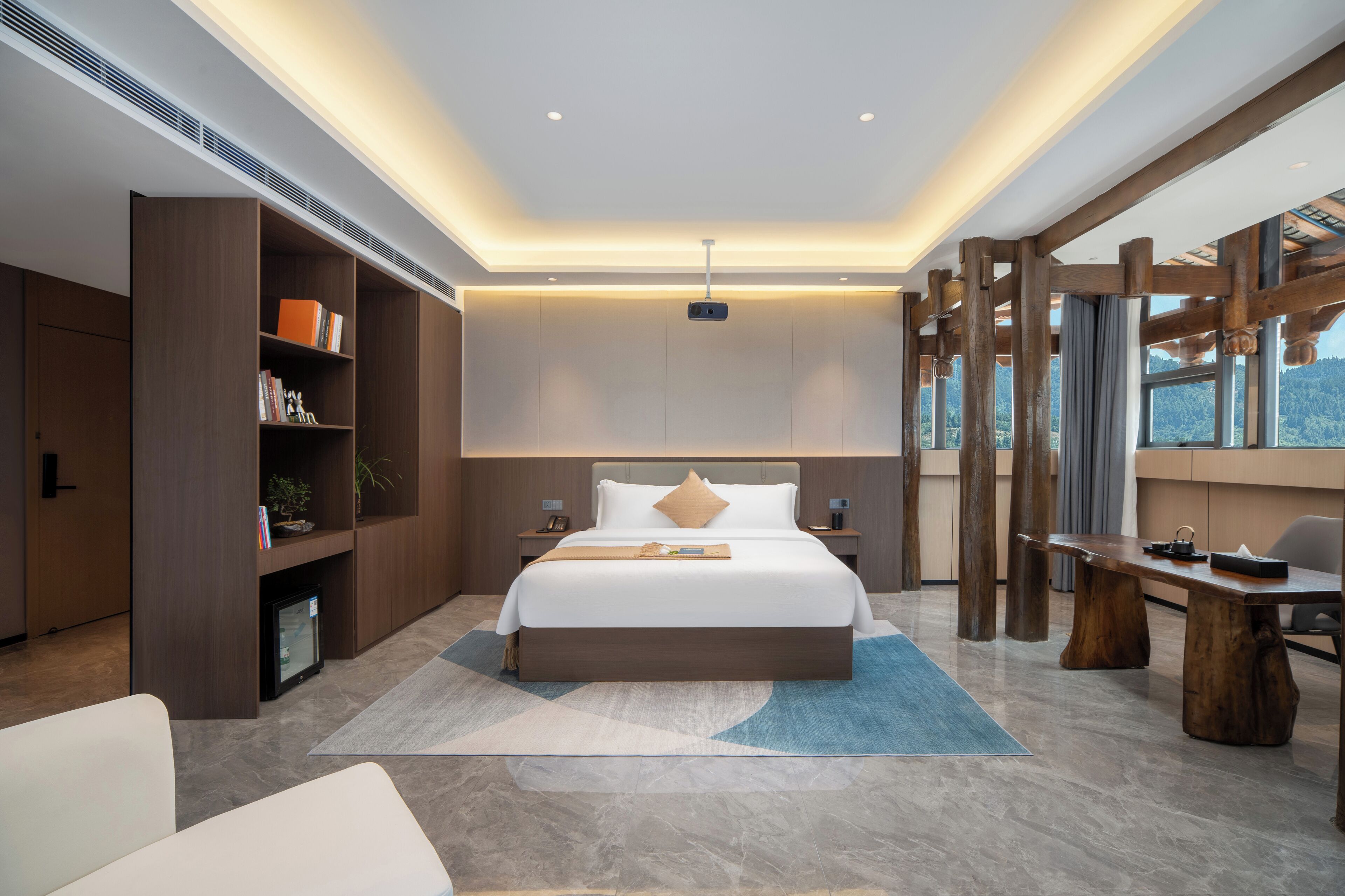 A modern hotel room with a large bed, built-in bookshelves, a desk, and a view of the outdoors.