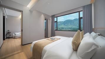 Una habitación de hotel moderna con una cama grande, vistas al exterior y un área de descanso separada.