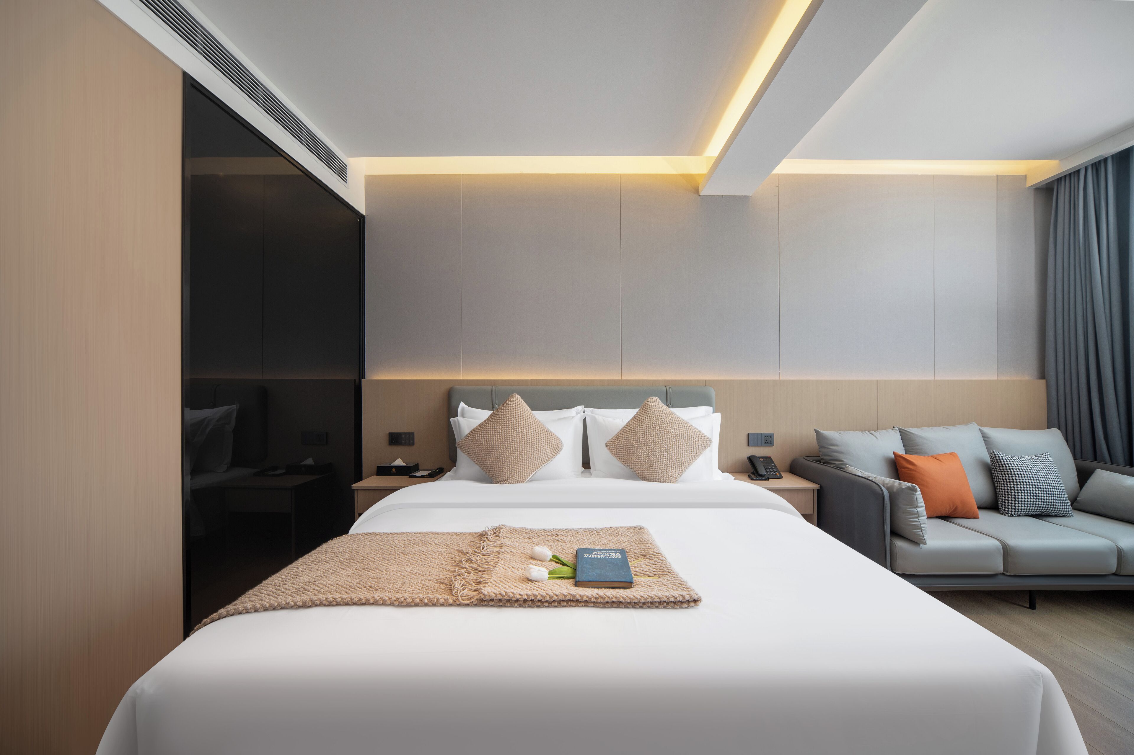 Una habitación de hotel moderna con una cama grande, un sofá y un escritorio.