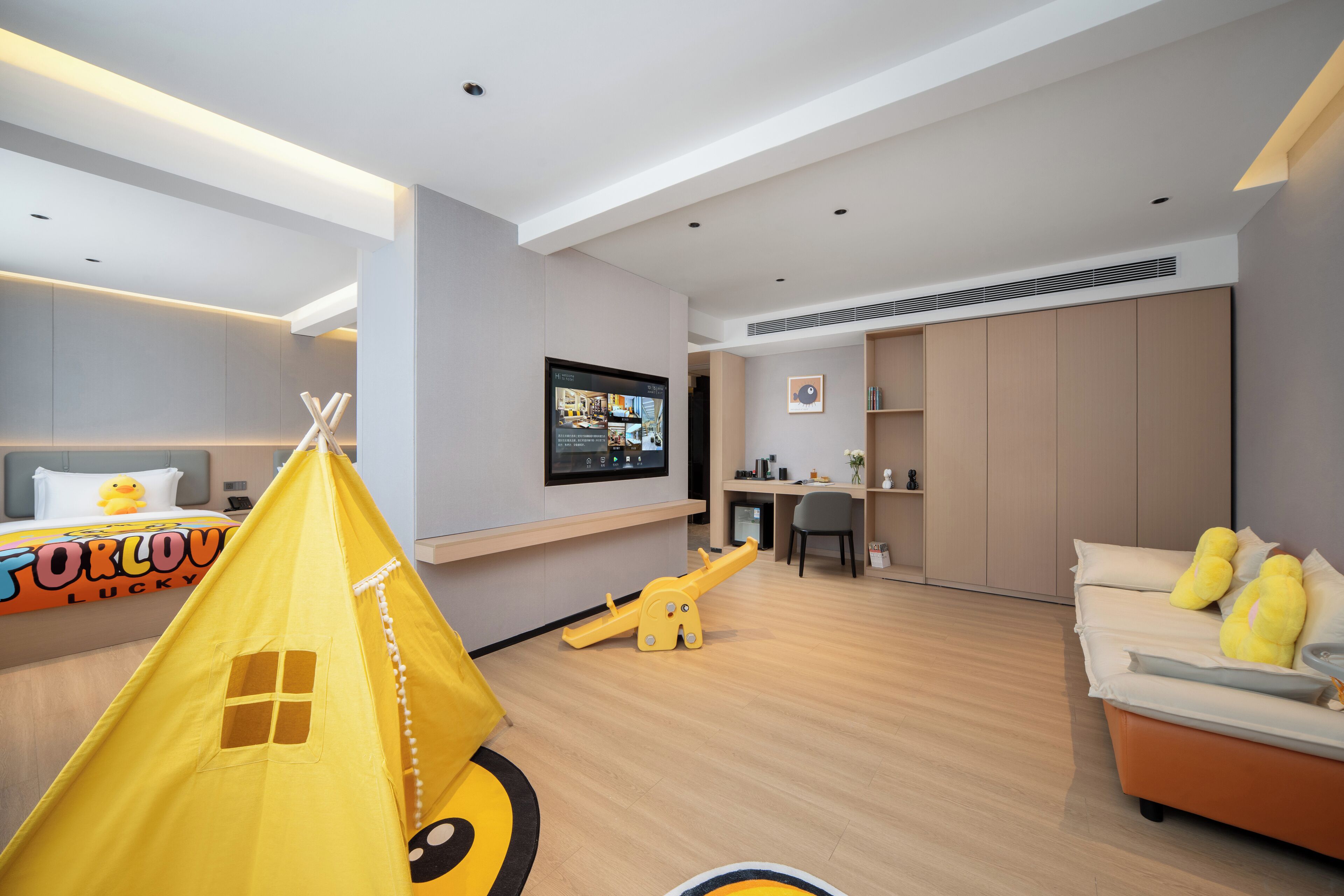 Una habitación de hotel moderna con cama, zona de juegos, escritorio y espacio para sentarse.