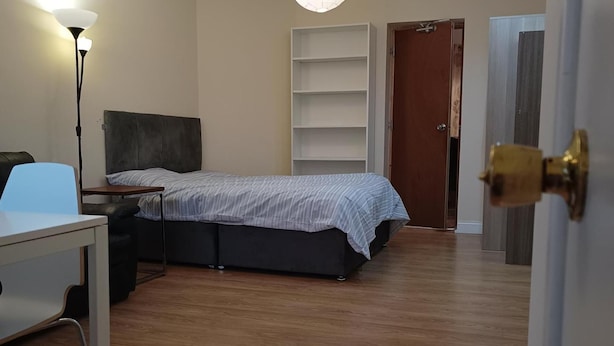 Ein Schlafzimmer mit Bett, Schreibtisch, Stuhl, Kleiderschrank und einer Tür.
