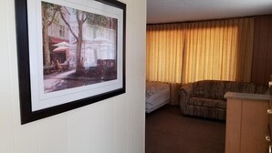 A room with a framed picture on the wall, a sofa, a chair, and a wooden cabinet.