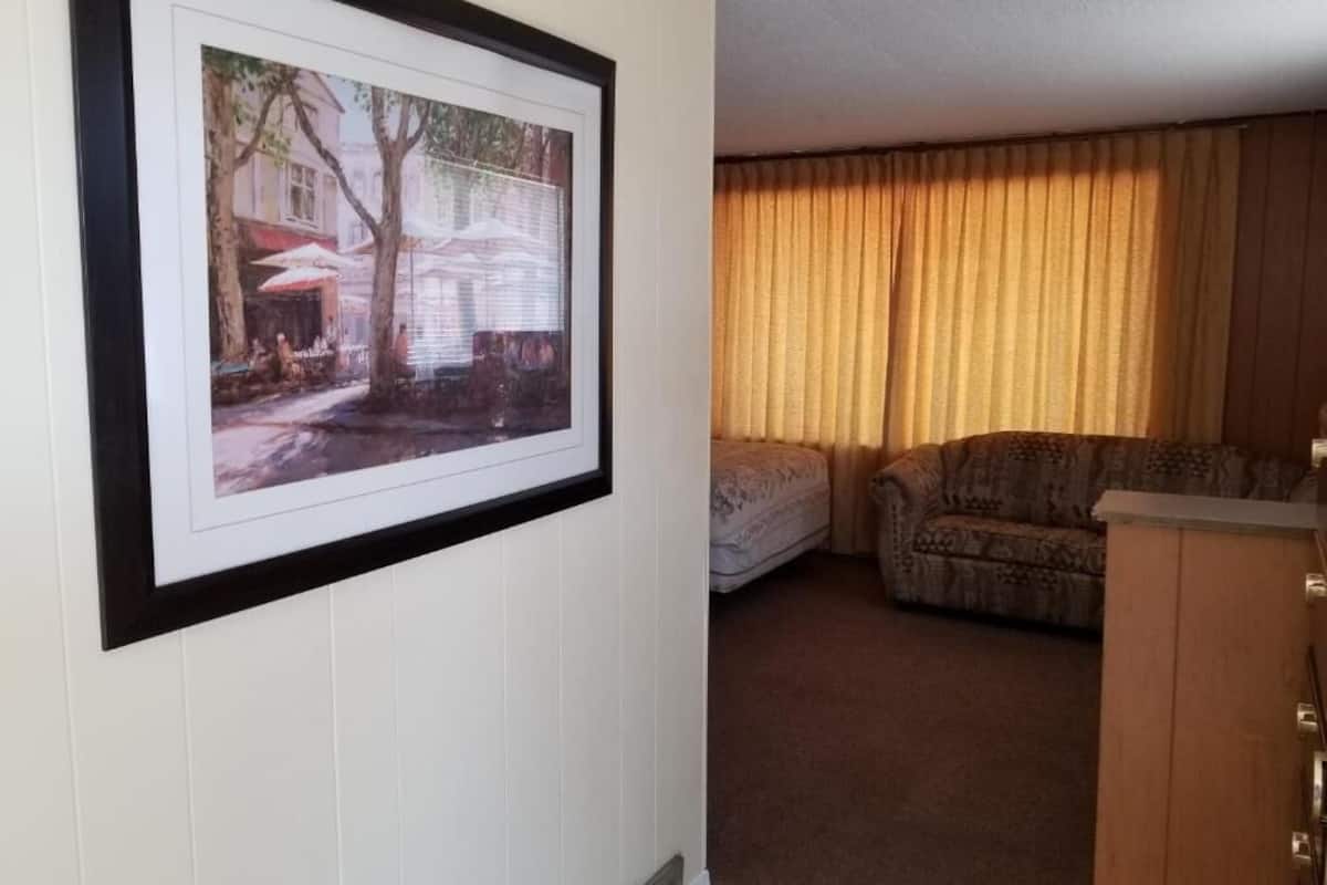 A room with a framed picture on the wall, a sofa, a chair, and a wooden cabinet.