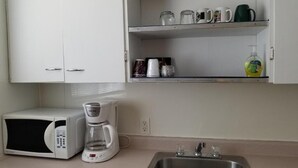 A kitchenette with a microwave, coffee maker, and a stainless steel sink.