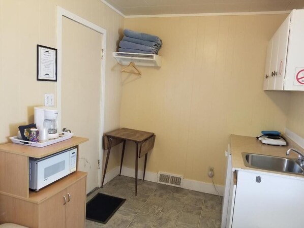 A compact kitchen with a microwave, coffee maker, and a small sink. - Melsask Motel (Melville)