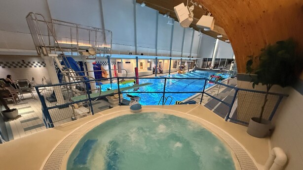 Una piscina interior con un trampolín y un jacuzzi.