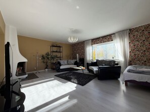 Un salon avec une cheminée, un canapé, une table basse et une fenêtre avec des rideaux.